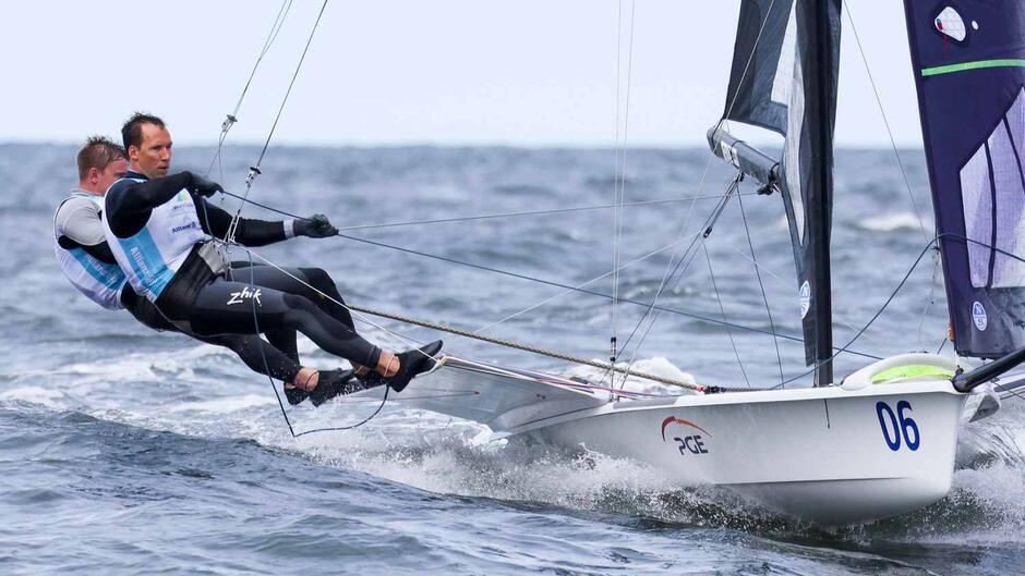 Dwóch żeglarzy na łodzi, wystają ciałami poza łódkę