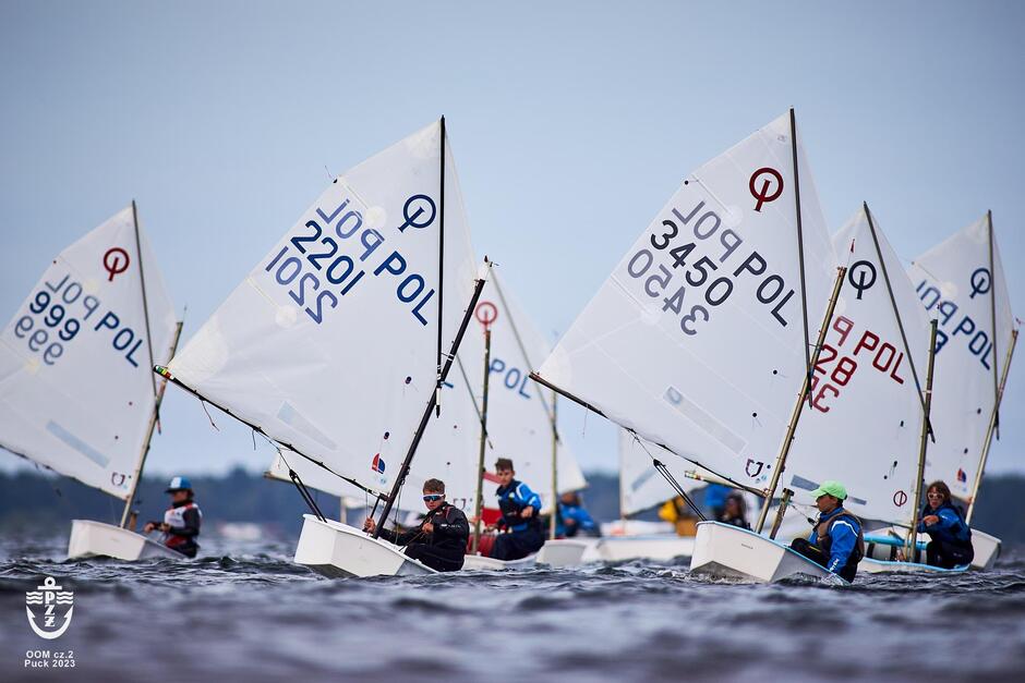 Łódki z żaglami i żeglarzem na pokładzie płyną na wodzie 