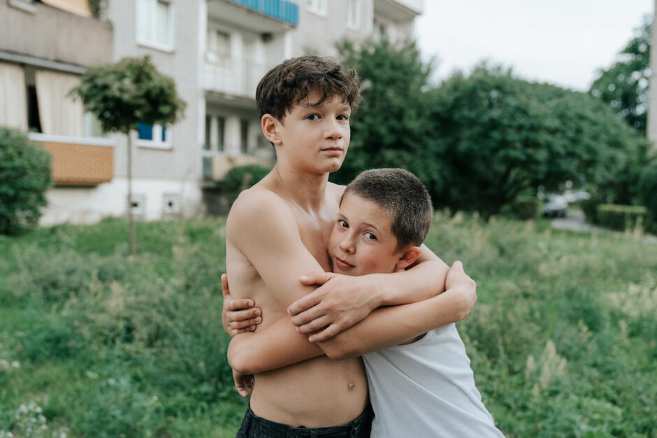 dwóch chłopców przytula się przed blokiem