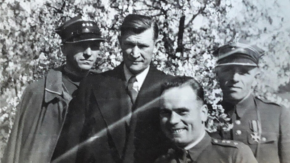 Czarno-białe zdjęcie przedstawiające trzech żołnierzy i mężczyznę w cywilu