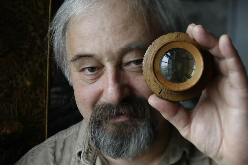 portret starszego mężczyzny z brodą trzymającego obiektyw fotograficzny