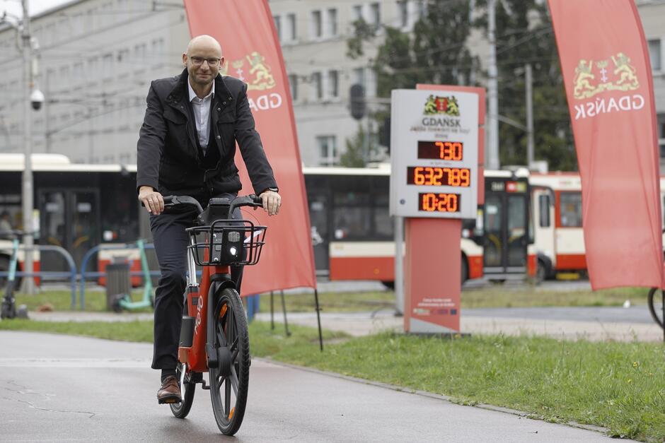na zdjęciu wiceprezydent gdańska piotr kryszewski, który jedzie na rowerze, jest ubrany w garnitur