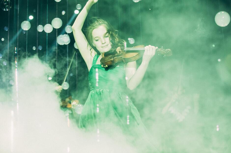 młoda kobieta w sukni na scenie ze skrzypcami