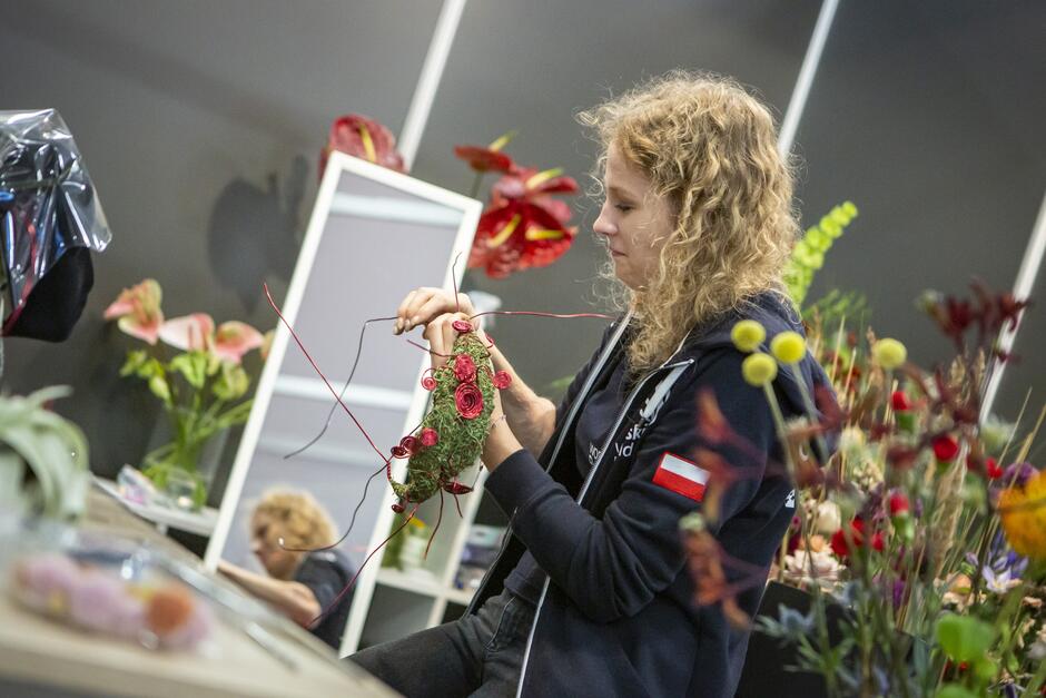 młoda kobieta układa kompozycję kwiatową