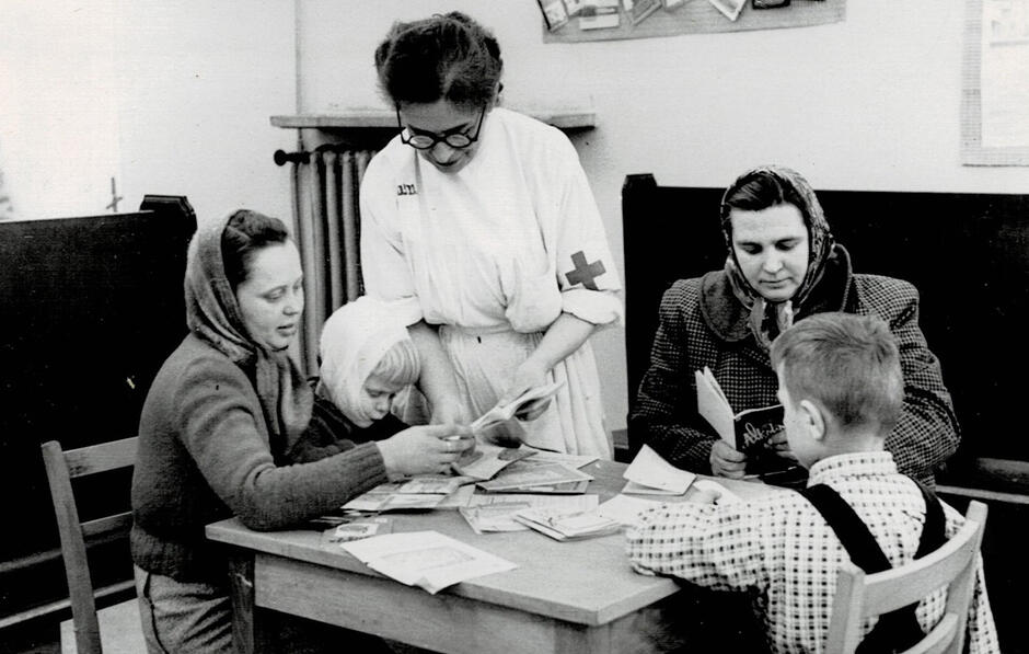 Czarno białe zdjęcie, dwie kobiety w chustach z dziećmi oraz lekarka