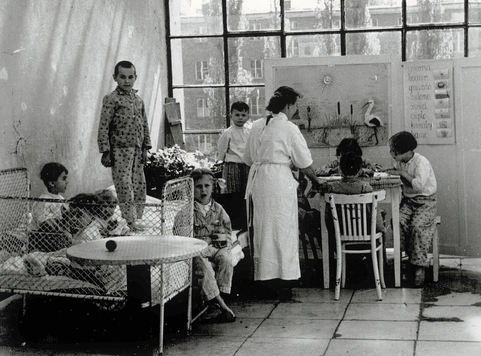 Zdjęcie czarno-białe, kilkoro dzieci uczących się w sali szpitalnej