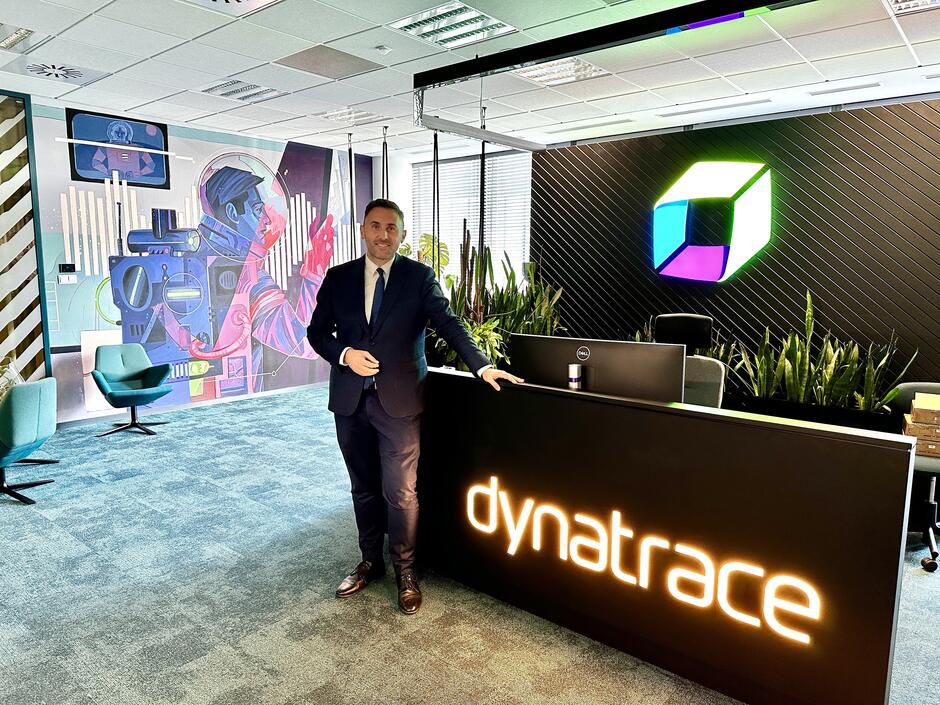 Uśmiechnięty mężczyzna w garniturze w siedzibie firmy o nazwie Dynatrace