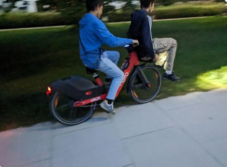 jedna osoba jedzie na rowerze, druga siedzi w koszyku