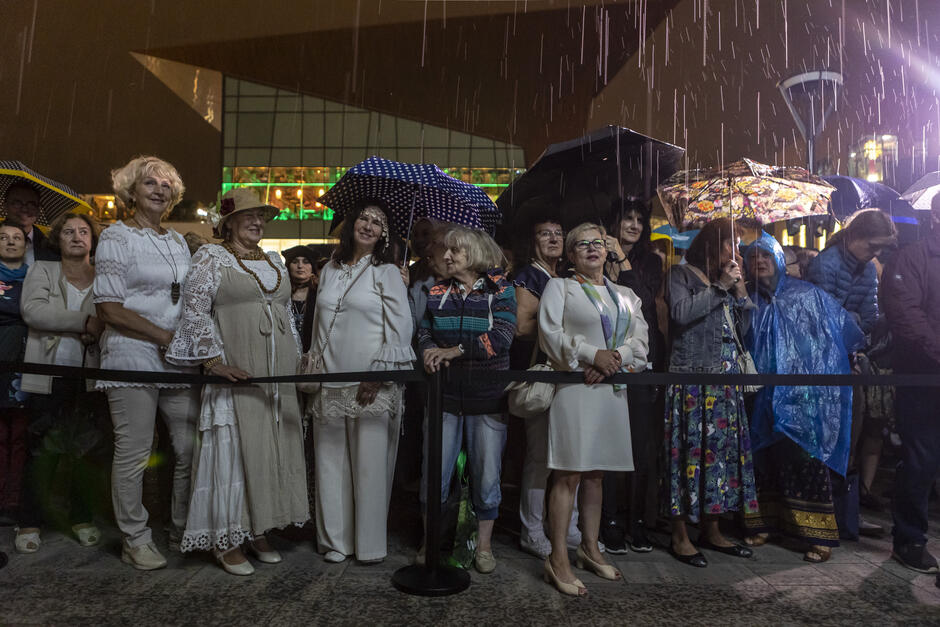 deszcz nocą, pod parasolami kobiety z widowni