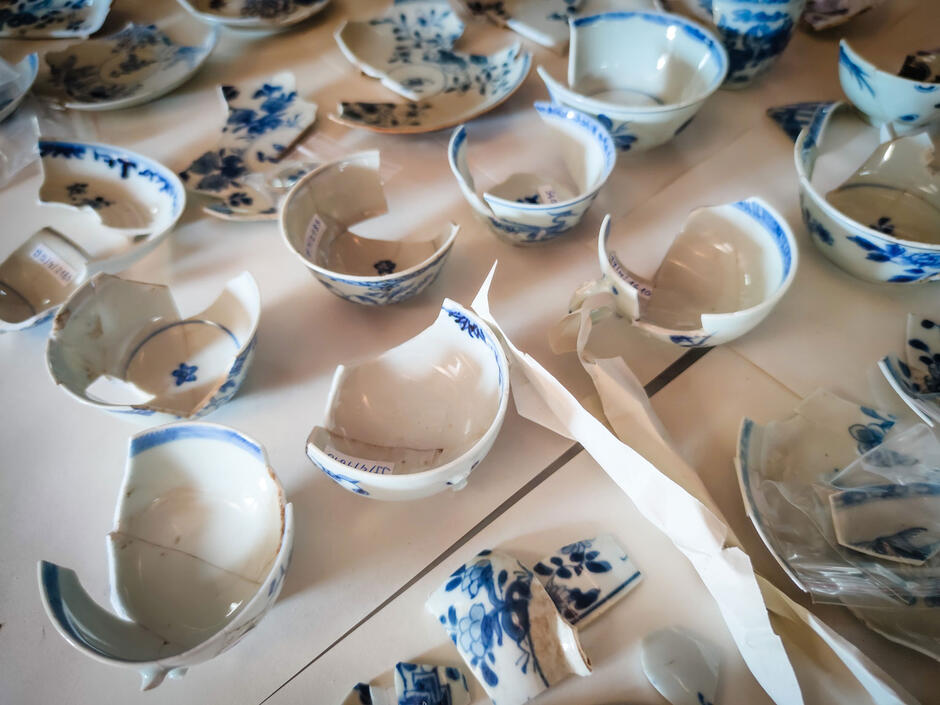 Potłuczone miseczki porcelanowe z niebieskimi rysunkami rozłożone są na na stołach