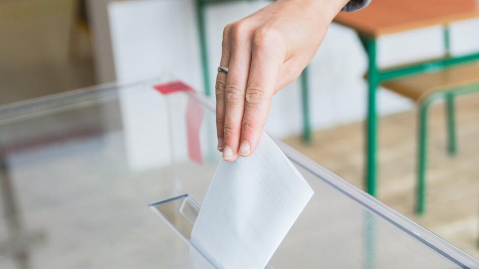 Dłoń wrzucająca kartę do urny wyborczej