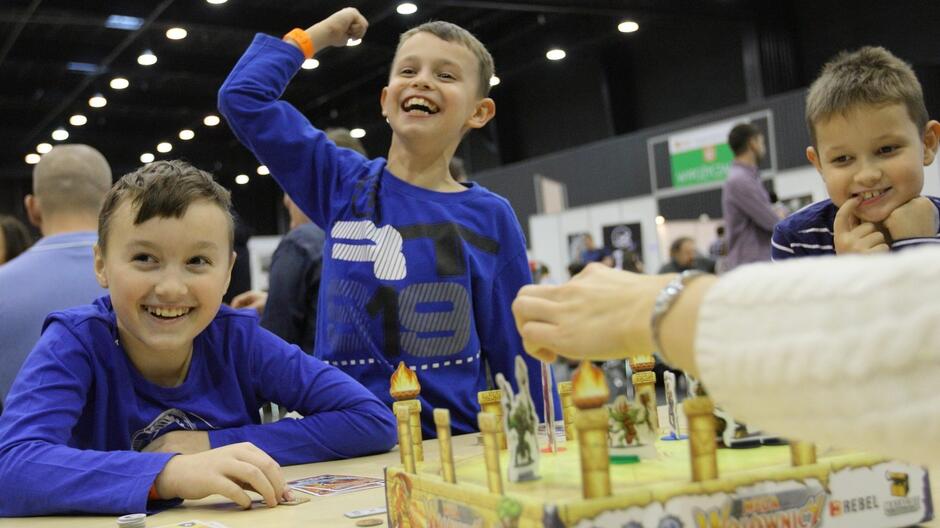 Trzech uśmiechniętych chłopców grających w grę planszową