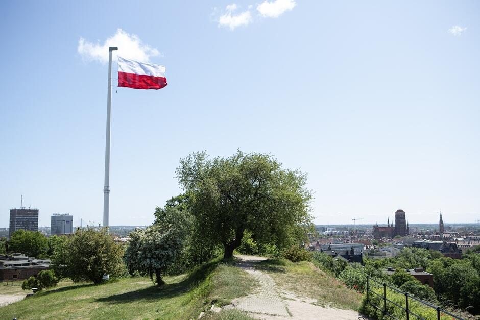 Maszt z flagą na wzgórzu, w tle miasto