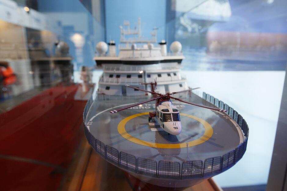 na zdjęciu miniaturka statku, z lądowiskiem, na którym stoi mini helikopter