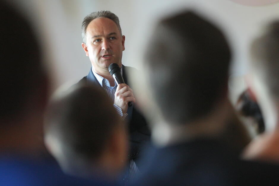 mężczyzna w średnim wieku na debacie z mikrofonem w dłoni