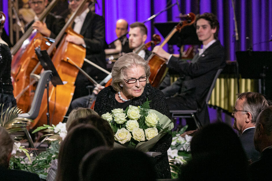 starsza kobieta na scenie odbiera bukiet kwiatów