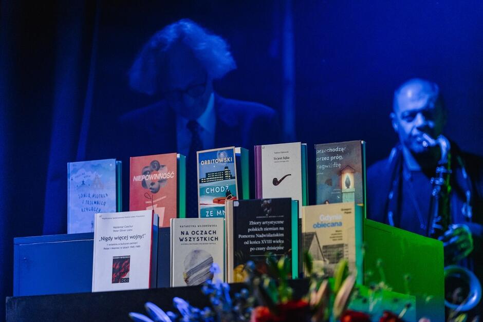 książki nominowanych ustawione na stole na scenie