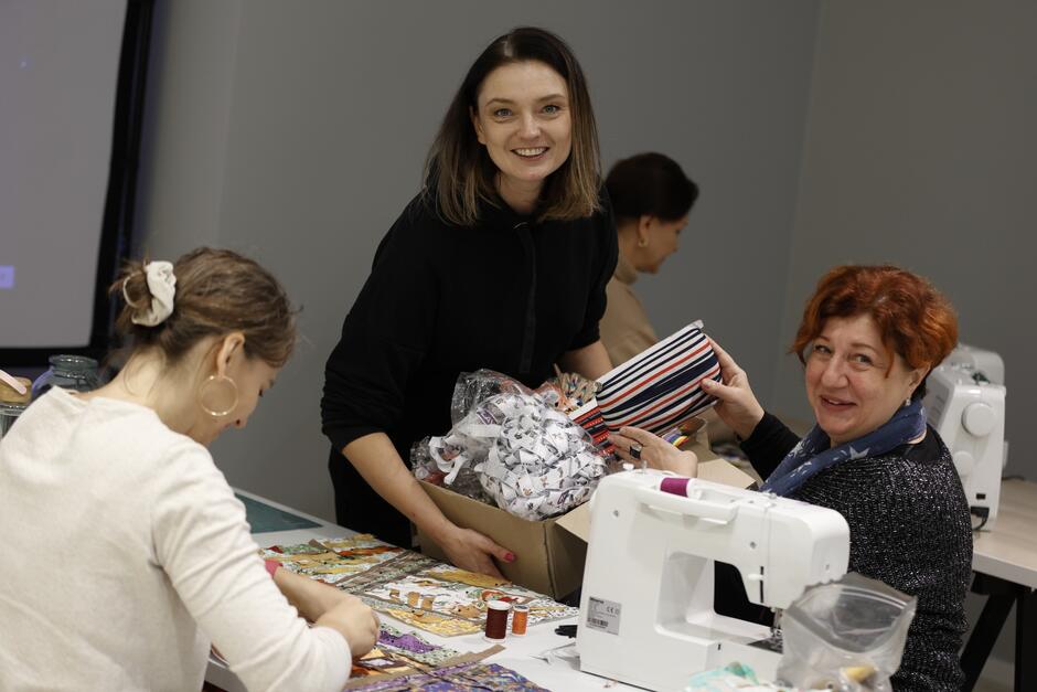 trzy kobiety na zdjęciu, jedna trzyma karton