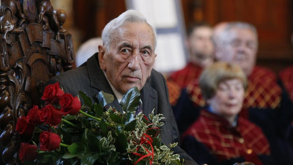 Starszy mężczyzna w pozycji siedzącej z bukietem czerwonych róż