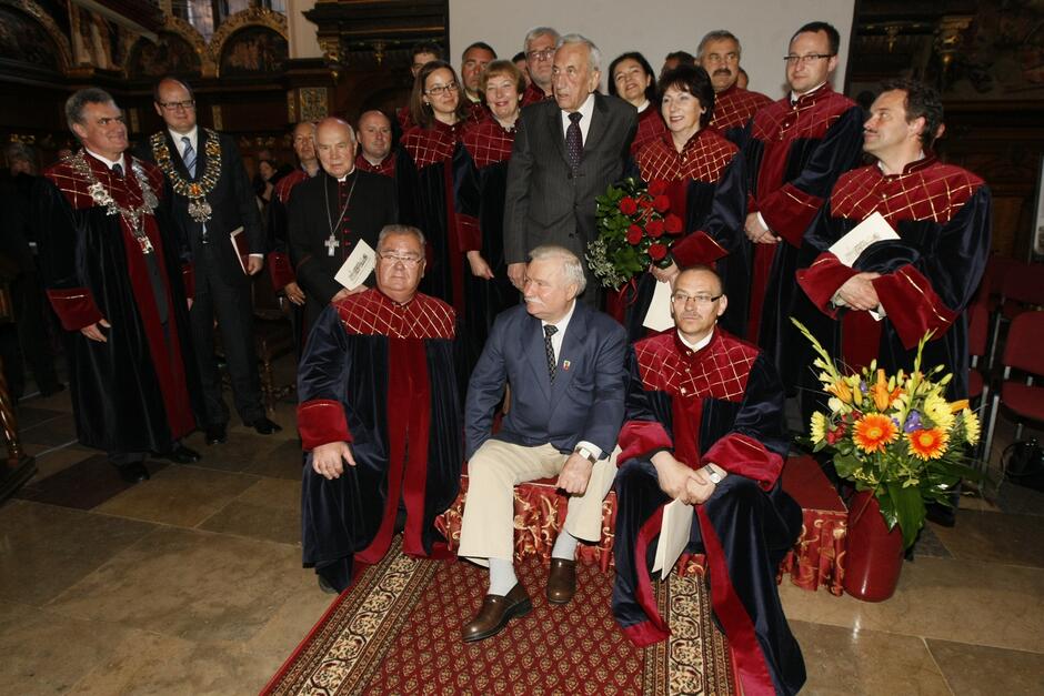 Zdjęcie zbiorowe radnych w uroczystych strojach i kilku osób ubranych w garnitury