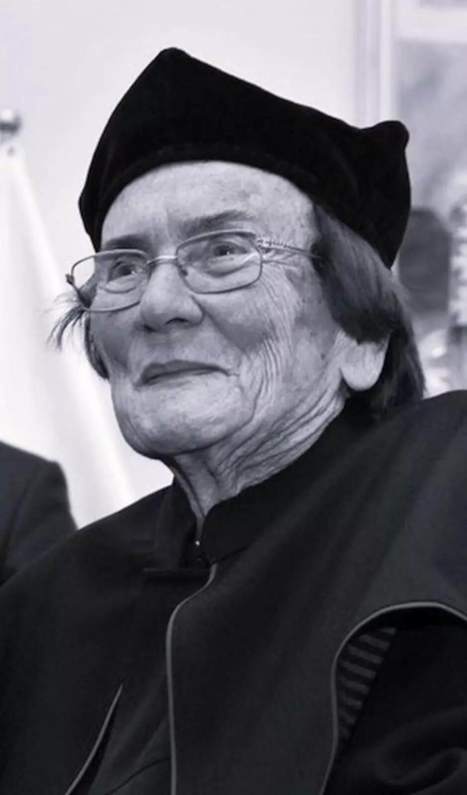 Czarno-białe zdjęcie: twarz kobiety w okularach w czapce rektorskiej na głowie 