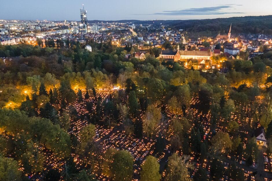 rozświetlony cmentarz u panorama miasta wieczorem