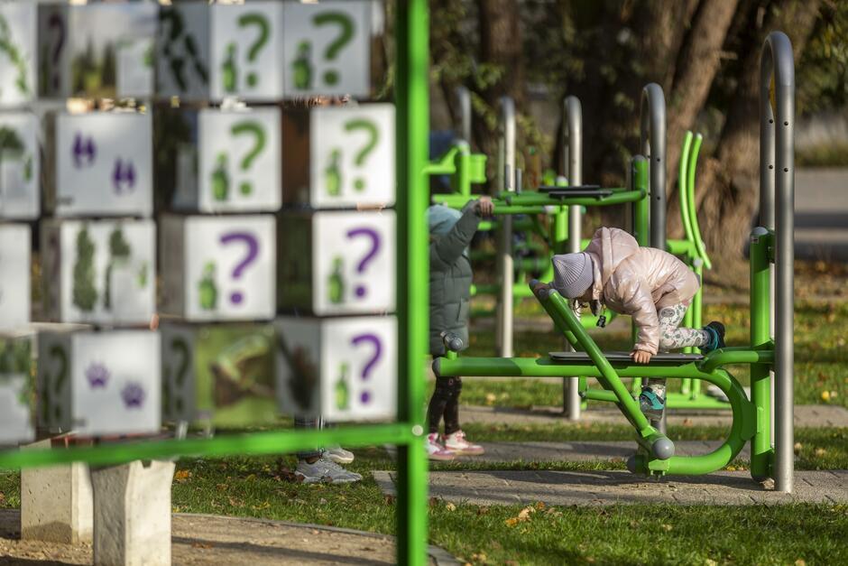 na zdjęciu urządzenia zabawowe i siłowni plenerowej, widać w tle dwoje bawiących się dzieci