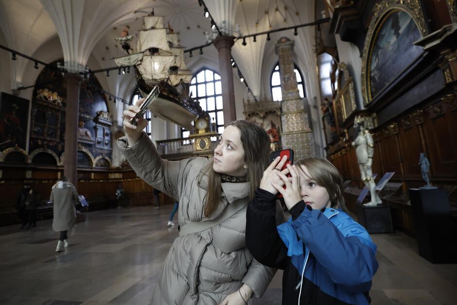młoda kobieta i ok 10letni chłopiec robią zdjęcia telefonami w Dworze Artusa