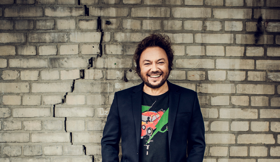 uśmiechnięty mężczyzna na tle ściany z jasnej cegły