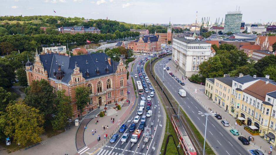 zdjęcie z drona, widać fragment ulicy Wały jagiellońskie, widać dwie jezdnie, jedna trzy druga czteropasmowa, jadą nimi samochody, wokół jezdni widać kamienice, w tle po prawej wysoki zielony wieżowiec