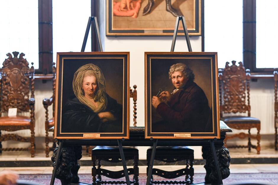 dwa portrety obok siebie prezentowane w zabytkowej sali