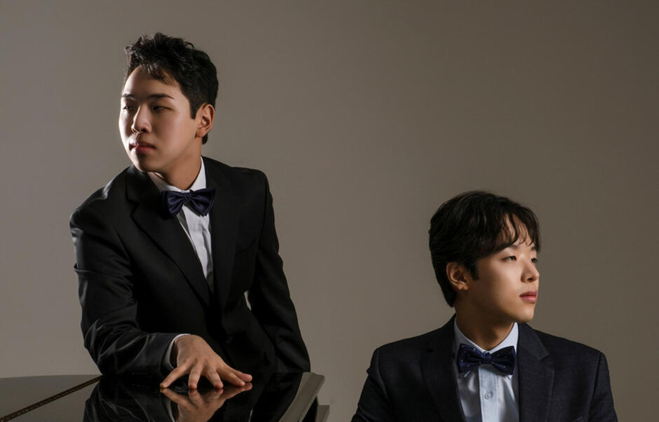 dwóch młodych azjatów w białych koszulach, czarnych marynarkach i czarnych muszkach