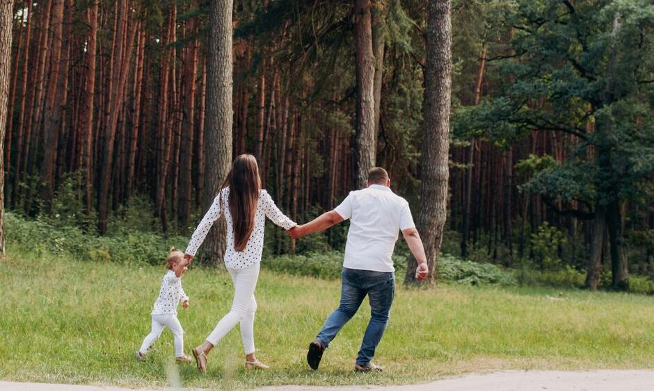 rodzina matka, dziecko i ojciec biegną leśną drogą w dal