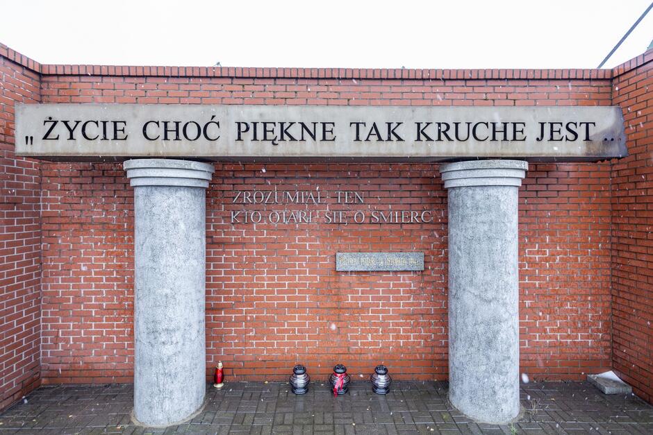 na zdjęciu pomnik, a pod nim ustawione znicze