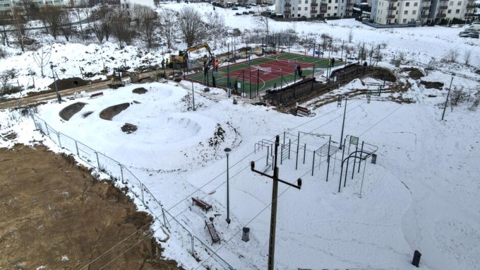 zdjęcie z drona, widać w oddali powstające boisko, a także pozostałe grunty pokryte śniegiem