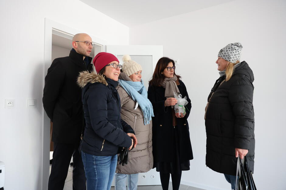 na zdjęciu cztery kobiety i jeden mężczyzna w średnim wieku w zimowych ubraniach, stoją w pustym pomieszczeniu
