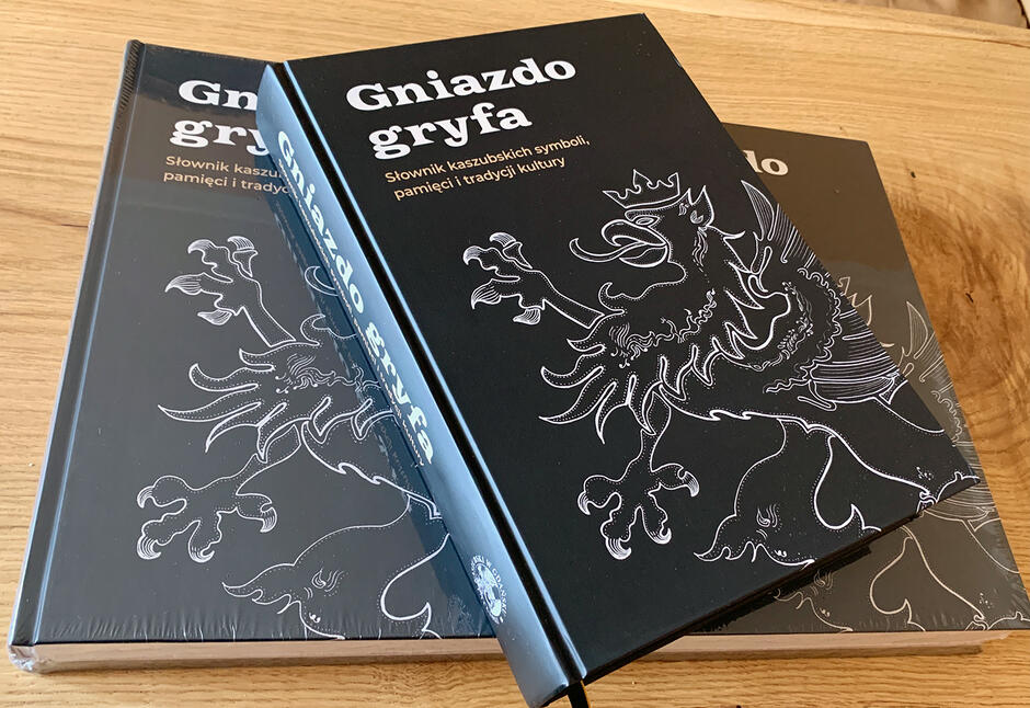 Na zdjęciu znajdują się dwie takie same książki. Ich okładki są granatowe z wytłoczonym tytułem: Gniazdo gryfa  i rysunkiem orła