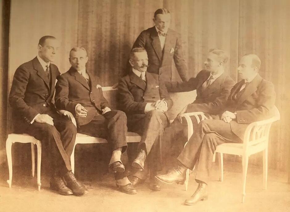 sześciu siedzących mężczyzn w garniturach