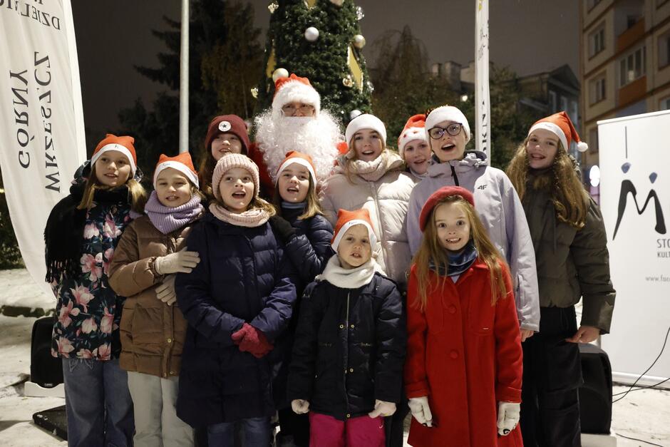 Mężczyzna w stroju świętego Mikołaja z kilkunastoma dziećmi dookoła