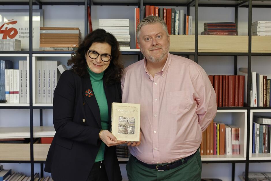 Kobieta po lewej, mężczyzna po prawej. Uśmiechnięci pozują do zdjęcia. Kobieta trzyma w rękach książkę Mieczysława Jałowieckiego 