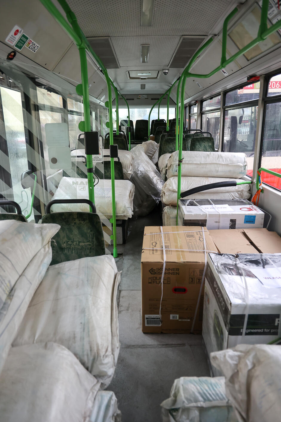 Wnętrze autobusu, w którym leżą kartony i wypełnione czymś worki 