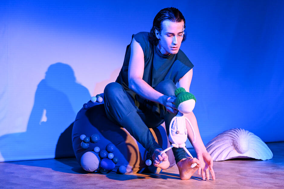 aktor siedzi na scenie, operuje lalką