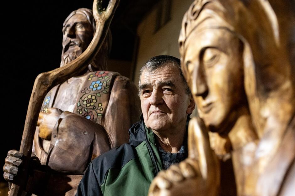 portret starszego mężczyzny i rzeźby z drewna dwóch realistycznych, ponadnaturalnej wielkości ludzkich postaci