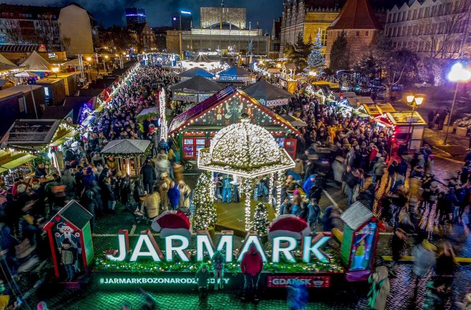 Jarmark Bożonarodzeniowy zimą, noc, napis ledowy Jarmark , tłumy ludzi przy stoiskach