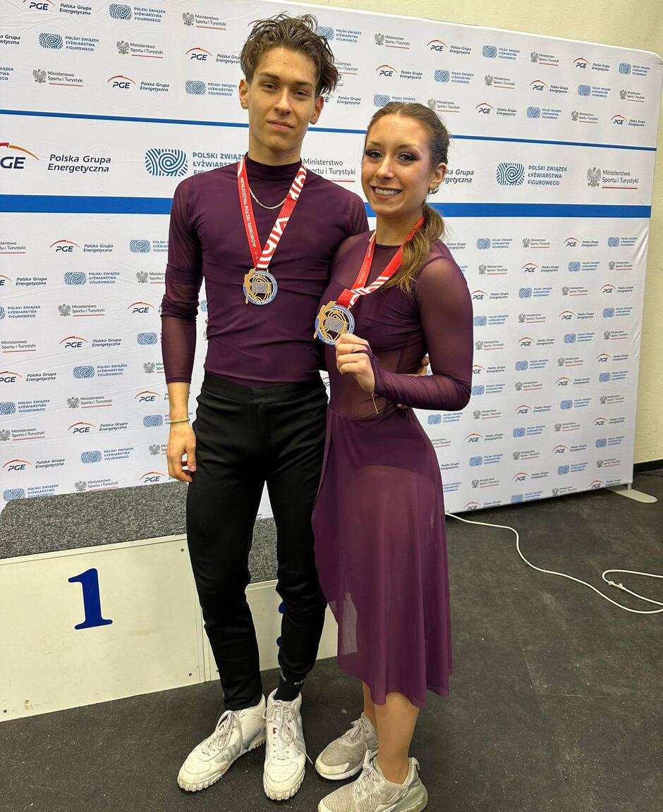 Mężczyzna i kobieta stoją z medalami na szyjach, uśmiechają się