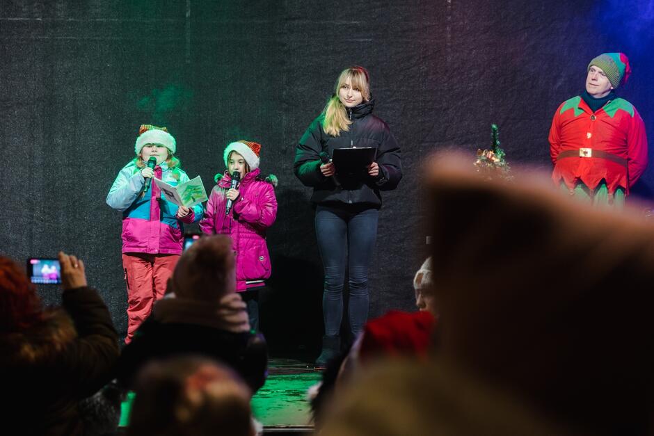 trzy dziewczynki w różnym wieku na scenie oraz mężczyzna przebrany za elfa 