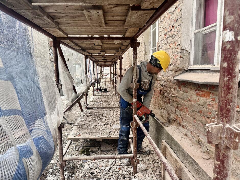 Pracownik budowlany na rusztowaniu przy elewacji budynku