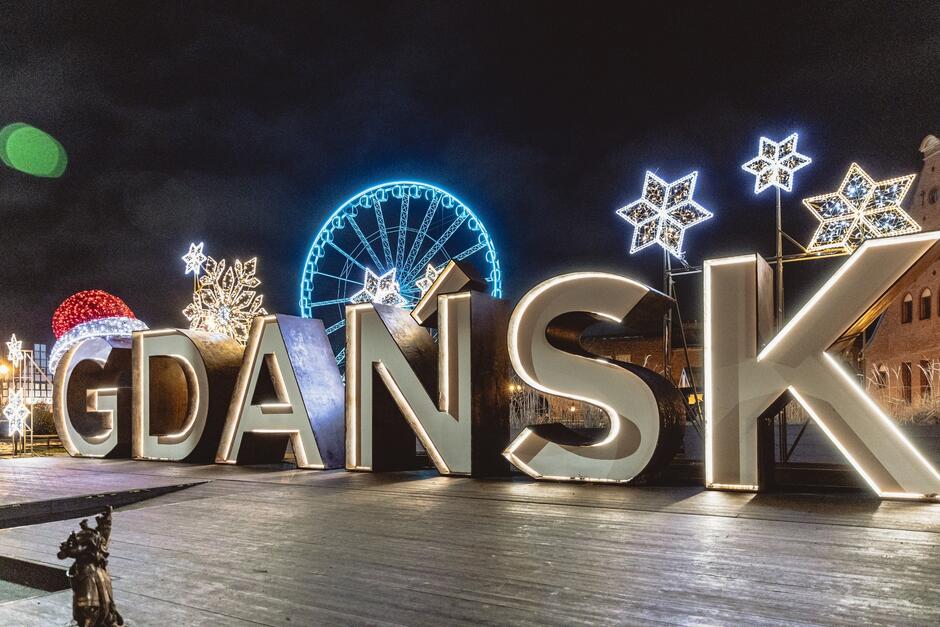 na zdjęciu duży napis Gdańsk z ozdobami świątecznymi, na literkach widać czerwoną czapę mikołaja i gwiazdki świetlne