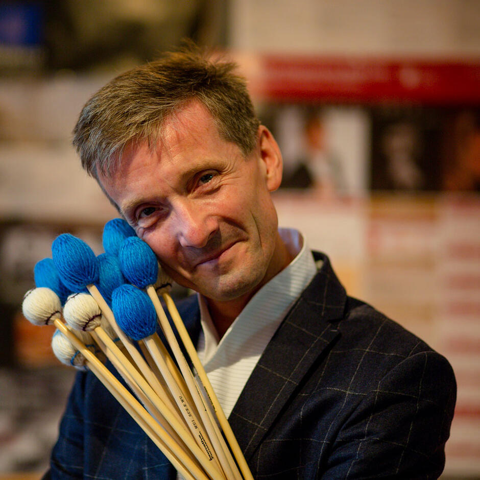 uśmiechnięty mężczyzna pozuje z pałeczkami perkusyjnymi