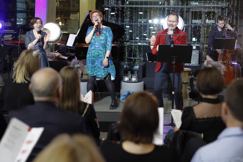 muzycy i wokaliści na scenie, przed nimi siedzi publiczność